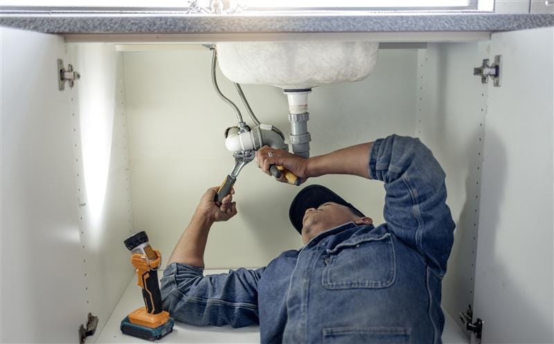 Plumber repairing pipes beneath a bathroom sink in Wesley Chapel