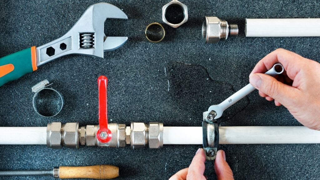 Plumber repairing a pipe valve with an adjustable wrench in Wesley Chapel