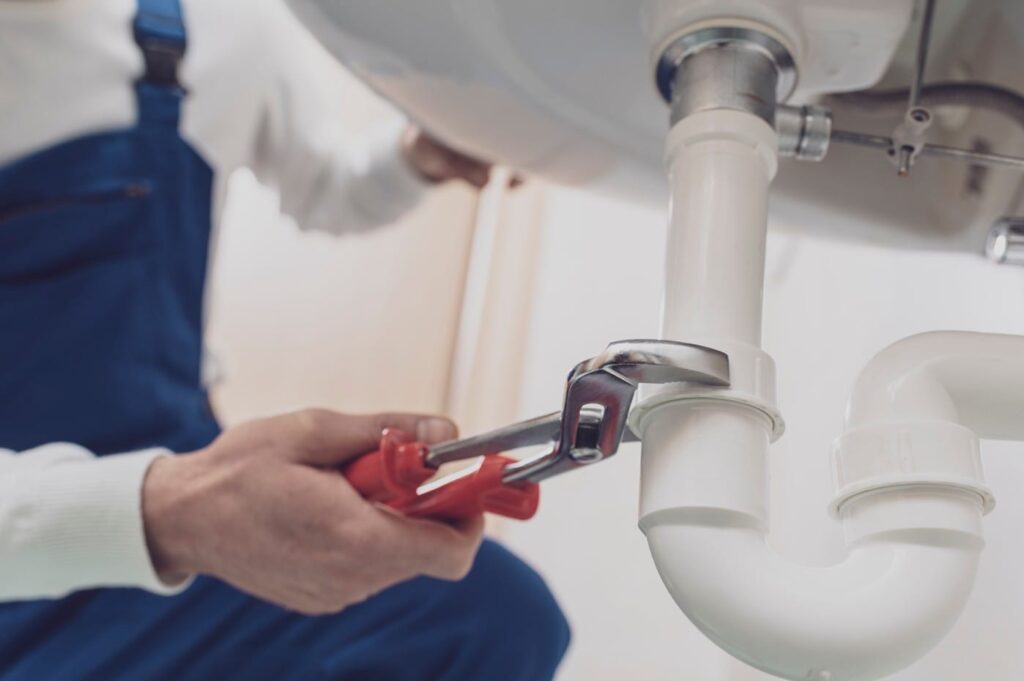 Plumber repairing a white drain pipe beneath a sink in Wesley Chapel