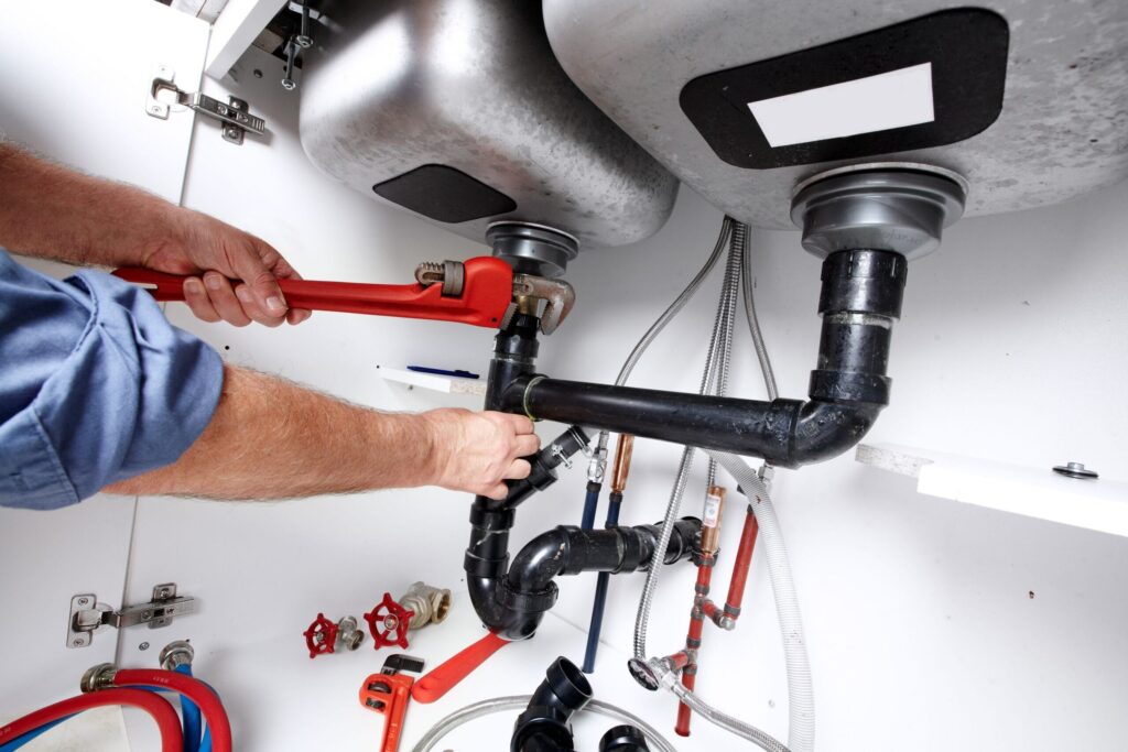Plumber repairing drain pipes beneath a kitchen sink in Wesley Chapel