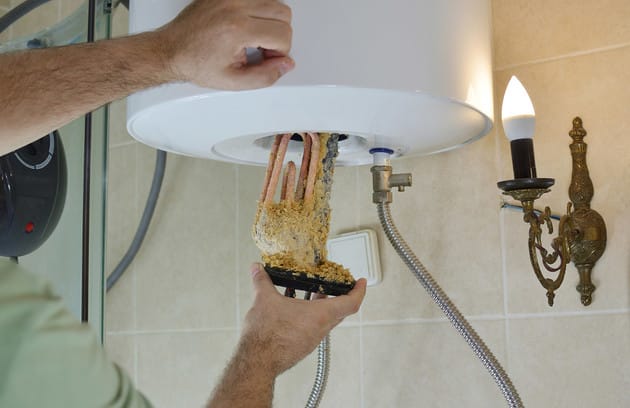 Technician removing mineral buildup from a water heater in Wesley Chapel